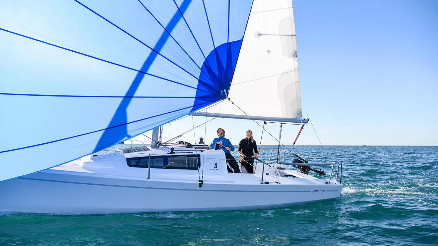 Beneteau First 24 with sails up and a couple onboard